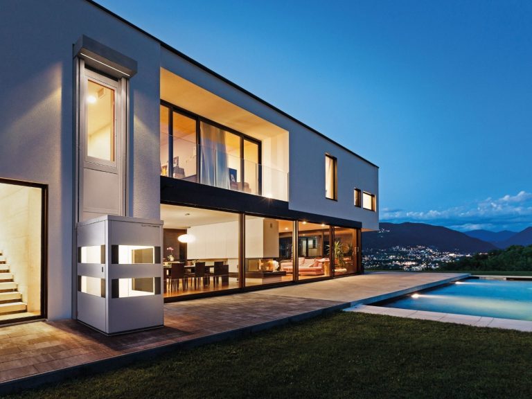 Moderne Villa mit großen Fenstern, Pool und Blick auf die Landschaft bei Dämmerung.